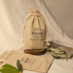 Syriana linen and cotton gift bag standing upright with drawstrings closed next to a flat bag