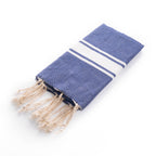 Folded Ipanema Fouta towel in navy blue with white stripes and tassels