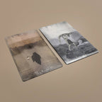 Two Tarot of Unknown Shadows cards lying flat showing The Hermit and another card with surreal landscapes