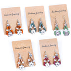 Meninas Bonitas Cork Flower Accessories Handmade Earrings 4x1.5cm – front view – five pairs of cork drop earrings in orange, teal, green, beige, and burgundy displayed on kraft paper cards.