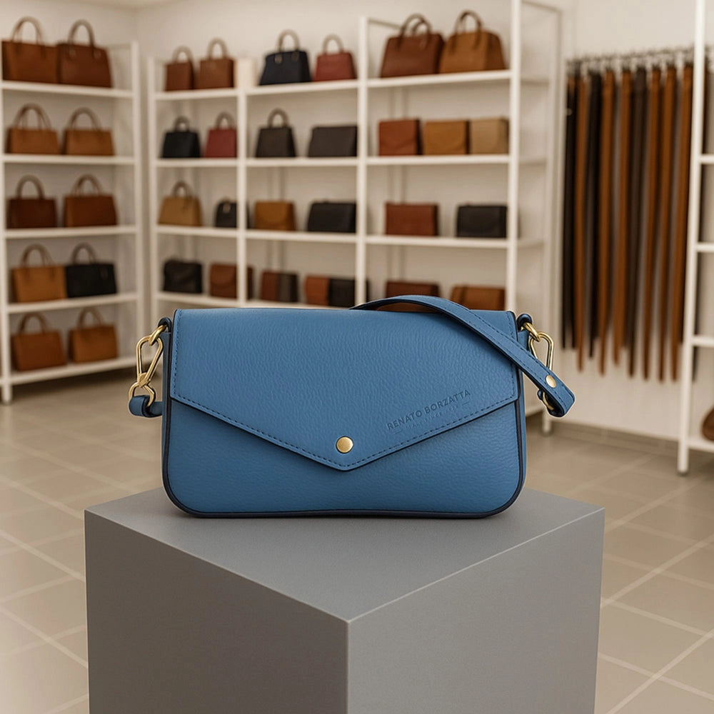 Renato Borzatta Avio Blue Leather Small Shoulder Bag 22x12x3cm – lifestyle – blue leather bag displayed on a grey pedestal in a boutique setting.